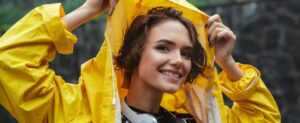 mulher com gabardine amarela a proteger o cabelo da chuva