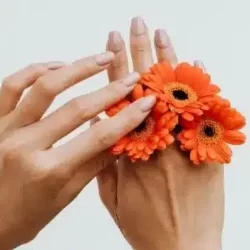 mãos com flor cor de laranja